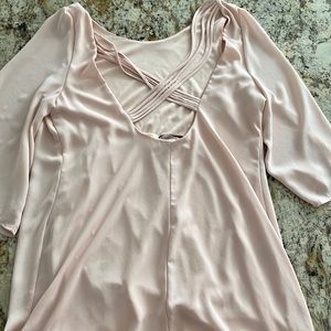 Blush blouse with low crisscross back and high front. Feminine sleeves and fit.